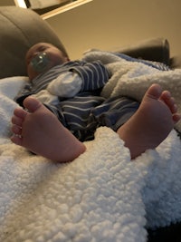 a baby laying on a couch with his feet wrapped in a blanket